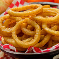 A serving of delicious breaded and deep fried golden brown onion rings.